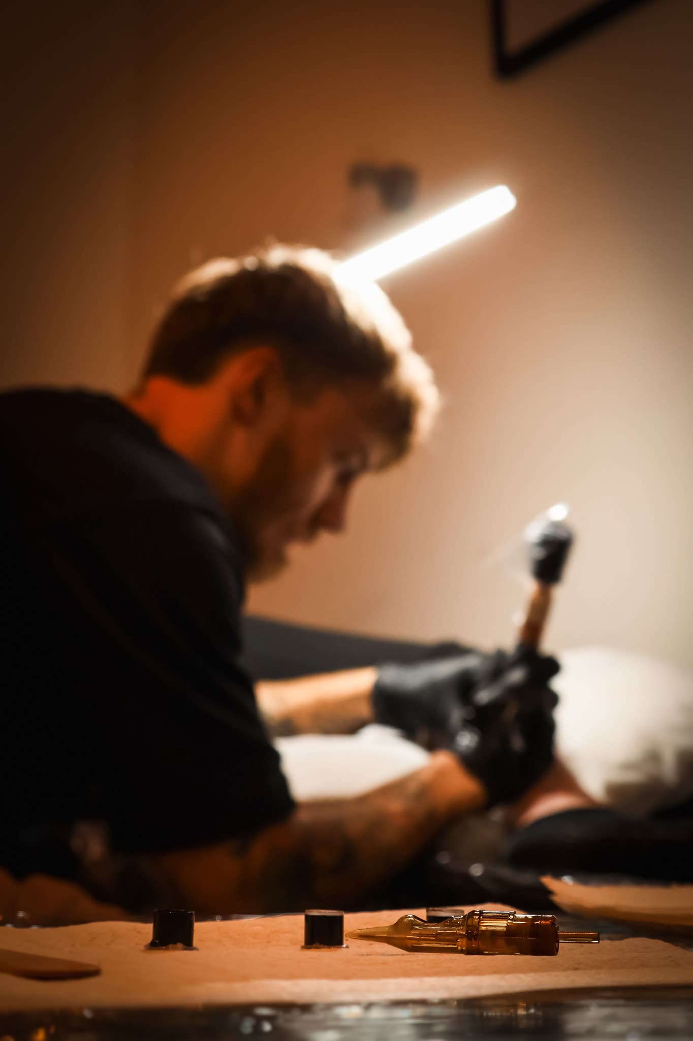 Tattoo artist at work under a single light